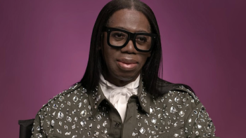 Reality Check: Inside ANTM TV show screenshot 3: J. Alexander wearing a leopaard top and black round glasses against purple backdrop.