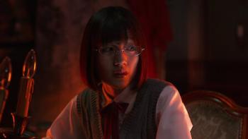Re: Mind screenshot 1: Mirei sits at the table, a red light glowing in the room. She looks with an expression of concern