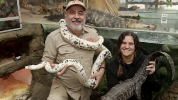 Reptile Royalty TV show screenshot 1: Jay brewer stands with a white snake around his neck while his daughter Laura stands to his right. 