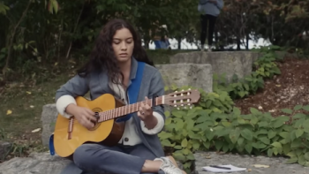 Ripple TV show screenshot 2: Aria plays guitar on a park bench.