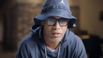 Ronaldinho: The One and Only TV show screenshot 1: Ronaldhino wears blue Nike bucket hat and sweat shirt with glasses and talks.