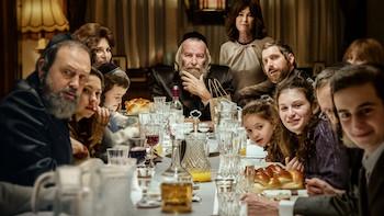 Still from Rough Diamonds: An Orthodox Jewish family of adults and children sits at a table filled with food and drinks.