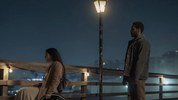 Santita TV show screenshot 3: Santita sits in wheelchair looking out at water at night under lamp post with her driver standing behind her.