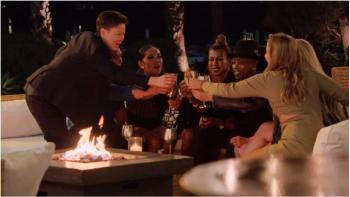 The Ultimatum: Queer Love: A group of women and non-binary people of many races sit around a fire pit clinking glasses.