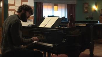 The Last Night at Tremore Beach screenshot: A White man plays piano as lamps gently lit up the room in the background