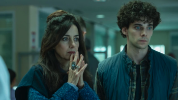 The Gardener TV show screenshot: A woman and man stand side by side and look ahead with concerns; the woman has her hands in a praying gesture