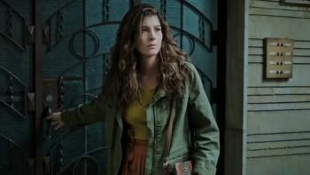 Delirium TV show screenshot: A curly-long-haired woman steps out of a door