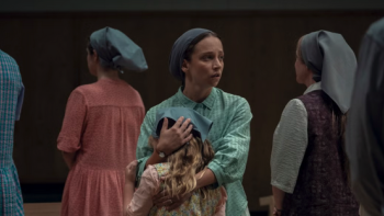 Unchosen TV show screenshot 2: Woman in a headscarf holds a child, surrounded by others wearing similar clothing.