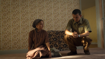 Unchosen TV show screenshot 3: A woman and a man in uniform sit on a carpeted floor in a dimly lit room.