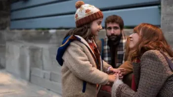 Shared Custody TV: Cris squats to Cloe's height and hold her hands, both smiling. Diego squats between them in the back, watching.