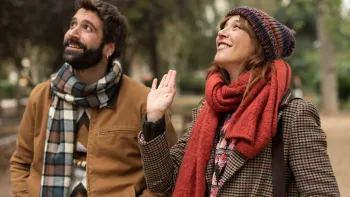 Shared Custody TV: Diego and Cris stand in an outdoor park wearing Fall outfits. They look up to the left and smile.