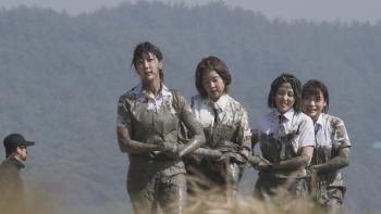 Siren: Survive the Island TV show screenshot - Four Asian women covered in mud struggle to carry a heavy pole.