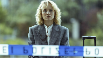 Sleeping Dog screenshot 2: Jule Andergast is in a suit looking forward at a police tape. 