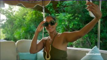 Solo Traveling with Tracee Ellis Ross TV show screenshot 2: Ross sits on an outdoor sofa with sky blue pillows. She's posing for a selfie