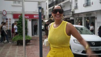Solo Traveling with Tracee Ellis Ross TV show screenshot 3: Ross smiles and walks around a shopping district; she wears a bright yellow mesh top