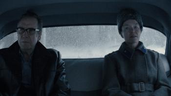 Rhys Ifans and Anna Maxwell Martin sit in the backseat. Ifans wears a leather coat with fur. Martin wears a coat and a fur hat.