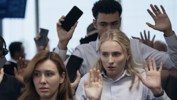 Steal TV show screenshot 2: Zara Dunne and other co-workers hold their phones and hands up in the air. 