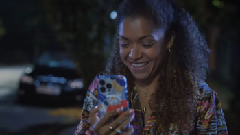 Still Up TV show screenshot 1: Lisa (Antonia Thomas) smiles at phone while walking at night. 