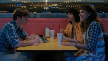 Stranger Things Season 4 screenshot 1: Will sits across from Eleven and Mike at a yellow formica table at a roller rink