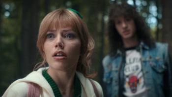 Stranger Things Season 4 screenshot 2: Crissy stares at something off-camera in wide-eyed horror, while Eddie is out of focus behind her