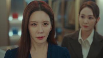 Jeong-eun Kim as Hwang Geum-ju, stands in front of a woman.