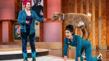 Stupid Pet Tricks TV show screenshot: Sarah Silverman poses on hands and knees with a goat on her back and the goat's owner standing next to her.