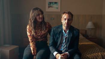 Sunny Nights TV show screenshot 2: Vicki and Martin sit together on a hotel room bed; his face is battered and bloody