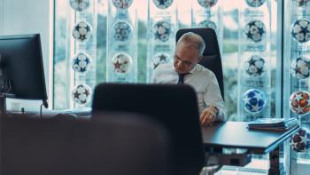 Giorgio Marchetti looking over papers at a desk in Super League: The War for Football.