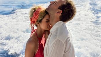 Supersex TV show screenshot: A woman rests her head against the neck of a man looking up with his eyes closed as they stand in front of the ocean.