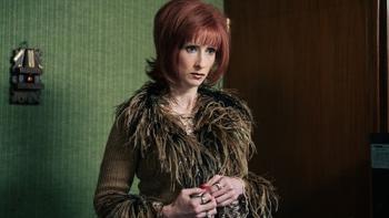 Superstar TV show screenshot 1: Tamara wears a feather-trimmed olive green jacket, standing with her hands clasped