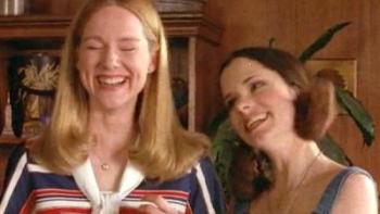 Tales of the City TV Show: Two women stand together in a living room with wood-paneled walls; they are laughing together. 