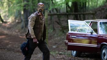 Teacup TV show screenshot 3: A male figure wearing a has mask walks outdoors, next to a maroon car with its door swung open.