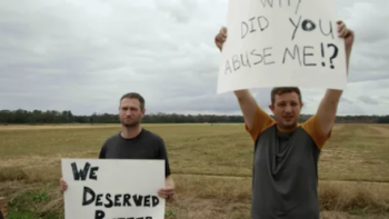 Teen Torture, Inc. TV show screenshot 3: Alan Knoll and other man hold posters in front of field. 