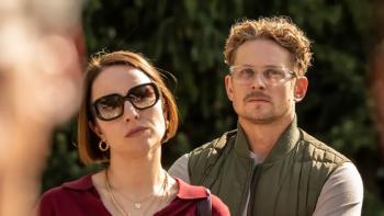 The Audacity screenshot 3: Sarah Goldberg wears a red blouse and dark shades. Billy Magnussen wears a grey shirt, green vest, and clear glasses.
