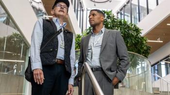 The Audacity screenshot 1:Rob Corddry and Andrew Bushell. Corddry wears a blue shirt, black vest, and jeans. Bushell wears a gray suit and blue shirt.