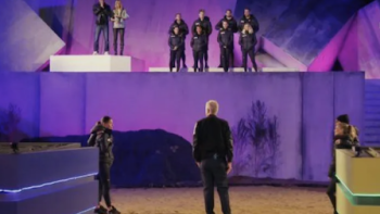 The Challenge Argentina screenshot-3: Host Marley has back to screen as he looks up at contestants standing on top of purple wall around The Arena. :