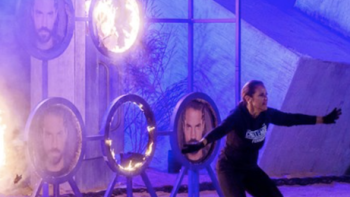The Challenge Argentina screenshot-2: Female contestant in black stands in front of black rings of fire featuring contestants' faces with arms forward.: