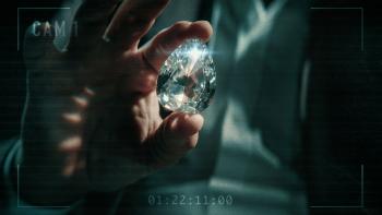 The Diamond Heist TV show screenshot: A white hand holds a massive shiny diamond.