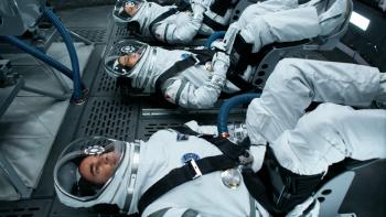 The First TV Series: Three astronauts in flight suits are strapped in seats with their backs oriented towards the ground.