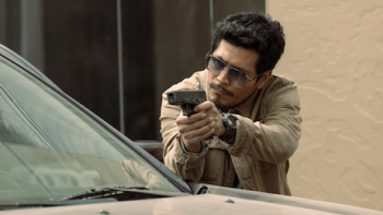 The Gringo Hunters TV show screenshot 3: Officer Nico Bernal posed to shoot behind car. 