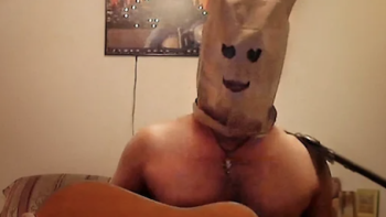 The Kings of Tupelo screenshot 3: A shirtless man with a paper bag over his head holds a guitar.