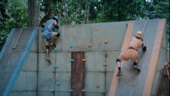 Two men climb up a wall during a challenge