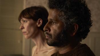 The Listeners TV show screenshot 1: Rebecca Hall and Prasanna Puwanarajah. Puwanarajah wears a brown sweater, Hall wears a white dress and necklace.