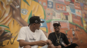 The Root of the Game TV show screenshot 3:Two men sitting in front of a colorful mural, smiling and talking.