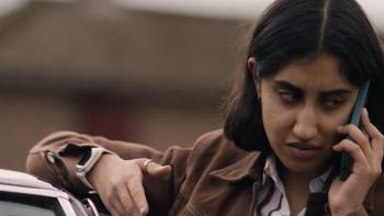 The Stolen Girl TV show screenshot 2: Ambika Mod leans against a car while talking on a phone. 