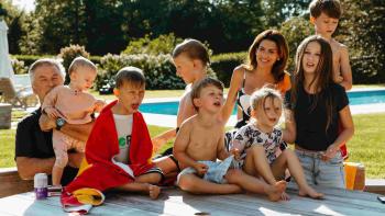 The Baldwins: Bright, colorful photo of all seven of of Alec and Hilaria Baldwin's children in front of a pool.