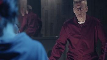 The Devil's Hour TV show screenshot 2: A man in a red jumpsuit is pictured standing, with a large mirror behind him reflecting his image.