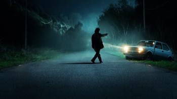 The Monster of Florence TV show screenshot 2: A silhouetted man in the blue light of the night points a gun at a car on a deserted road