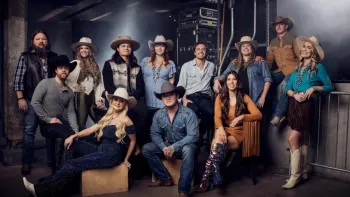 The Road TV show screenshot 1: 12 men and women, roughly 20-50 years old, stand in posed positions with country and western clothing and accessories.