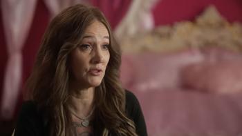 Thirst Trap TV show screenshot 3: A fan of William White's named Storm speaks to the camera, sitting in a bedroom decorated in tones of red and pink